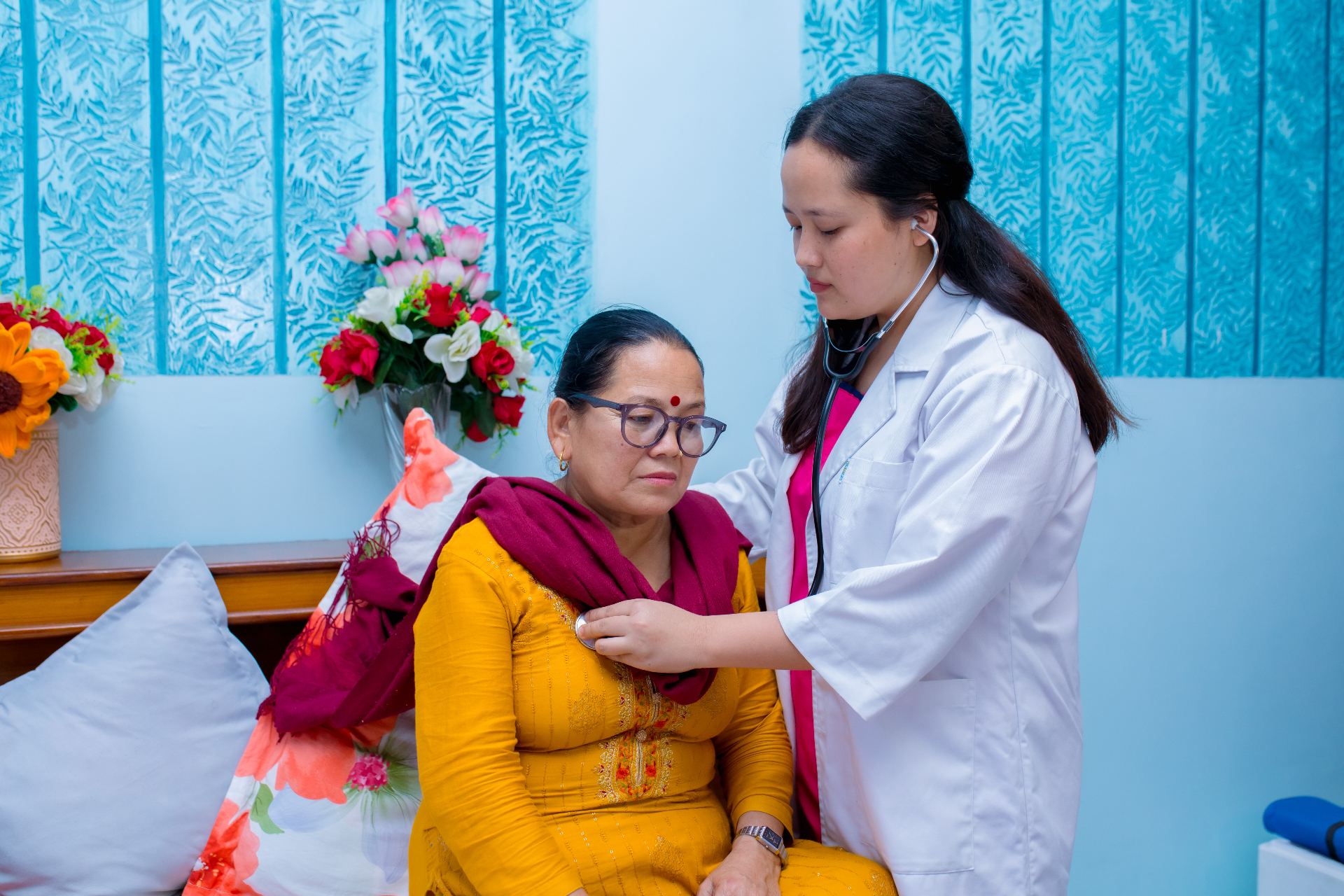 Doctor reviewing elderly patient with stethoscope during home visit