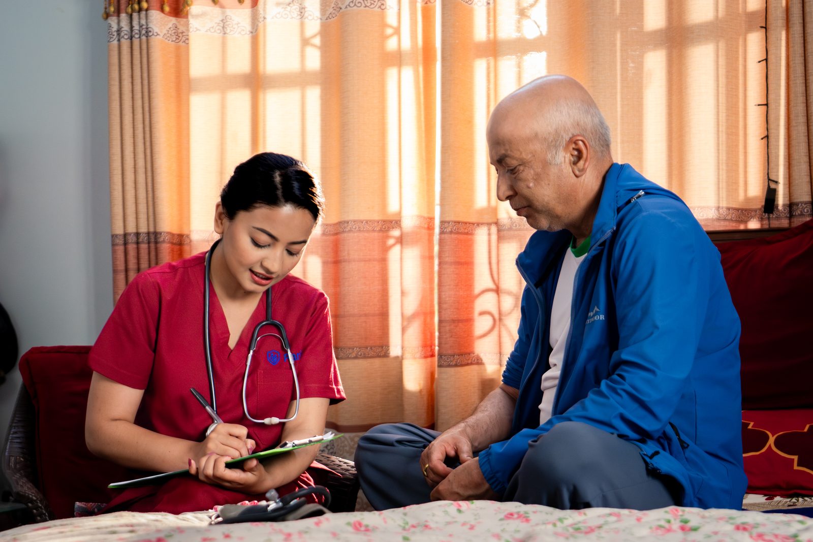 Nurse recording checkup notes with elderly patient at home