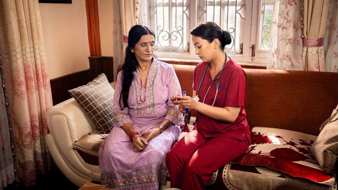 Nurse assisting patient with medication at home